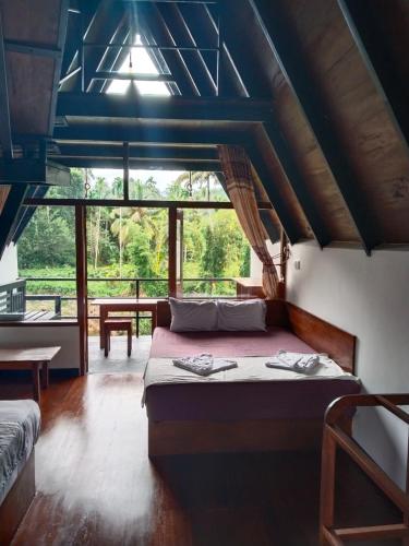 a bedroom with a bed and a large window at Sinharaja Riverside in Deniyaya