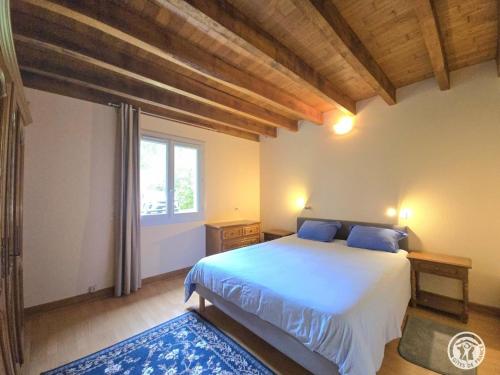 Un dormitorio con una cama con almohadas azules y una ventana. en Gîte rural à Saint-Cybranet avec piscine privée, animaux admis - FR-1-616-502, en Saint-Cybranet