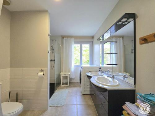 Un baño con dos lavabos, un inodoro y un espejo. en Gîte rural à Saint-Cybranet avec piscine privée, animaux admis - FR-1-616-502, en Saint-Cybranet