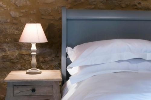 ein Bett mit blauem Kopfteil und einer Lampe auf einem Nachttisch in der Unterkunft Charming Mas With Medieval Church Views in Sainte-Croix-de-Beaumont