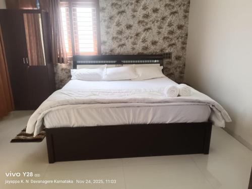 ein Bett mit weißen Laken und Kissen in einem Schlafzimmer in der Unterkunft Aakruthi Homestay in Davanagere