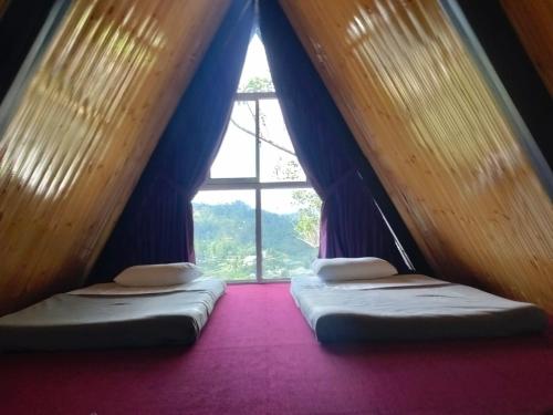 two beds in a room with a window at Bliss den in Bandarawela
