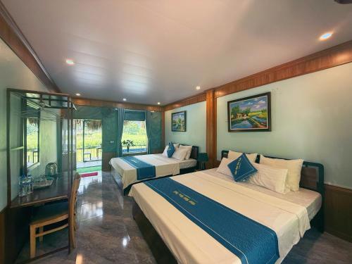 ein Hotelzimmer mit 2 Betten, einem Schreibtisch und Fenstern in der Unterkunft Trang An River Sunshine Bungalow in Xuân Sơn