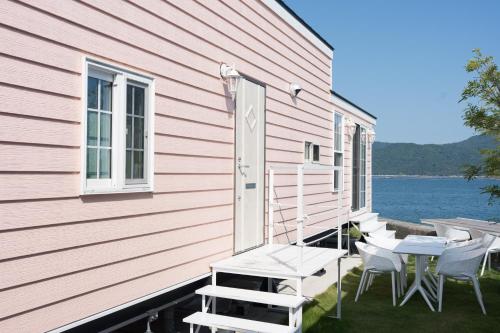 a pink house with chairs and a table on the side at 宮島リゾート Hauol'i in Hatsukaichi