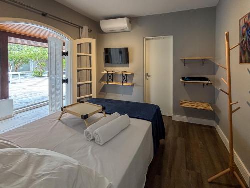 a bedroom with a bed with a tv on the wall at Moreno Guest House com Piscina, churrasqueira Praia de Itaguaré e Riviera in Bertioga