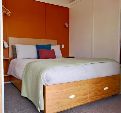 een slaapkamer met een groot bed met een oranje muur bij Redshed Studio Mangawhai in Mangawhai