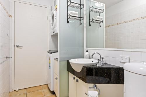 a white bathroom with a sink and a mirror at Byron Getaway @the Crest in Byron Bay