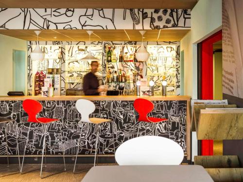 a bar with red chairs and a black and white wall at ibis Hotel Brussels Airport in Diegem
