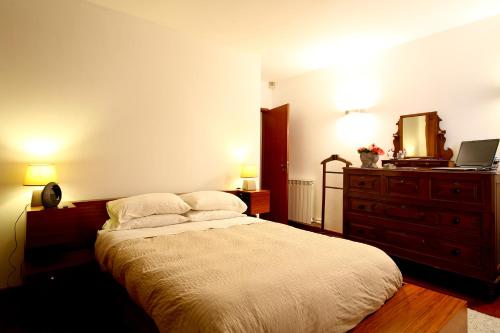 Un dormitorio con una cama con una cómoda y un espejo. en Casa da Miza, en Vilar do Pinheiro