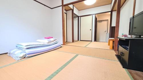 a living room with a tv and a pile of blankets at ビジネス旅館 錦荘 - Nishiki Guest House in Kadoma
