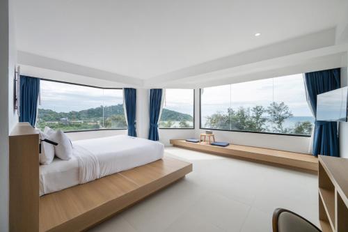 a bedroom with a large bed and large windows at Kokotel Rayong Beachfront in Ban Pak Khlong Phe