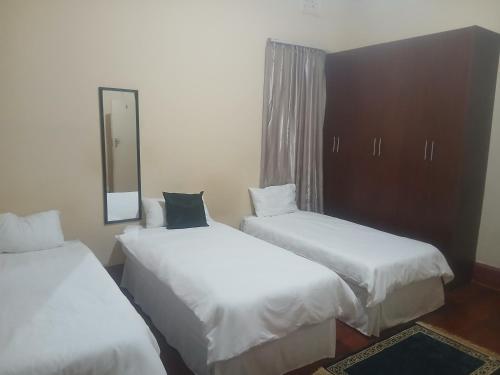 two beds in a hotel room with a mirror at Clark lodge at 272 in Durban
