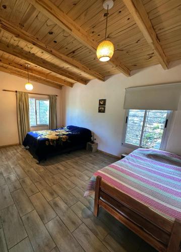a bedroom with two beds and a wooden ceiling at Cedro Azul in La Cumbre