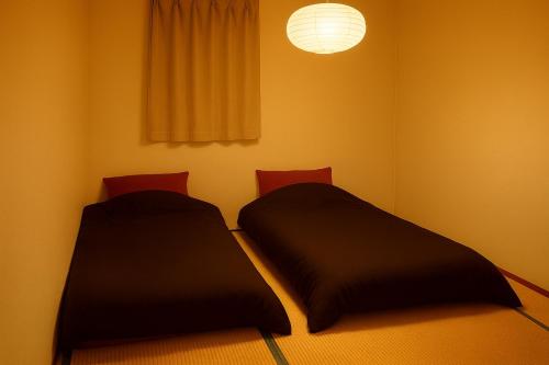 two beds in a small room with a lamp at ご当地ラーメン食べ放題 "The RAMEN HOTEL" -京都嵐山- in Kyoto