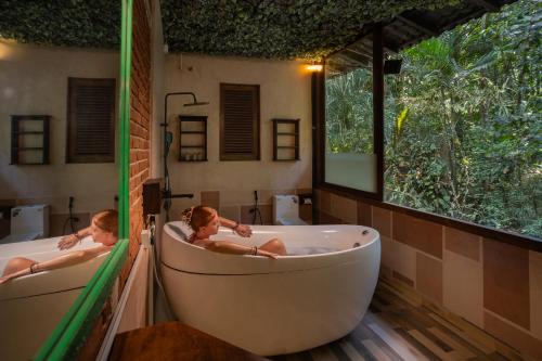 two people are sitting in a bath tub in a bathroom at Wild Monkey Jungle Villa - 4 Bedroom Villa in Unawatuna