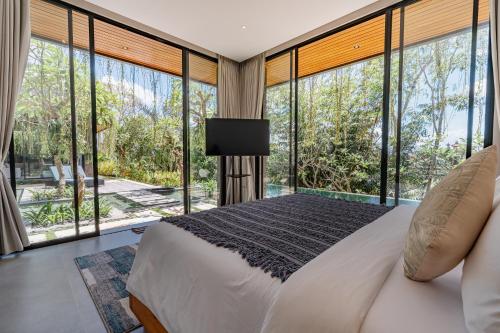 Un dormitorio con una cama y grandes ventanales. en Kalapa and Merica Luxury Villas Ubud, en Gianyar