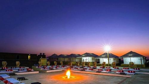 Un grupo de mesas y sillas con un fuego en el medio. en Desert camp Sam, en Sām