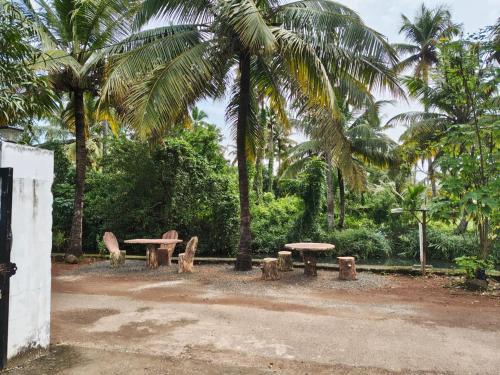 un parque con mesas y sillas y palmeras en Eha Mundro Island Homestay, en Munroe Island