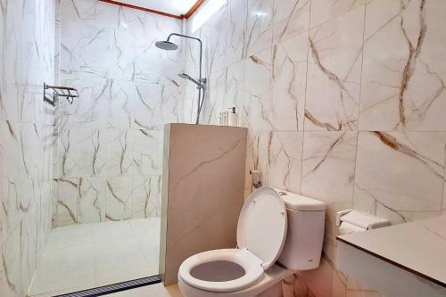 Un baño blanco con inodoro y ducha. en The Beach Huts Lembongan, en Nusa Lembongan