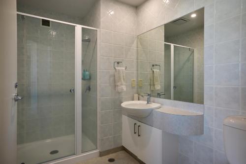 a bathroom with a sink and a shower and a toilet at Beaumont Apartments in Mount Maunganui