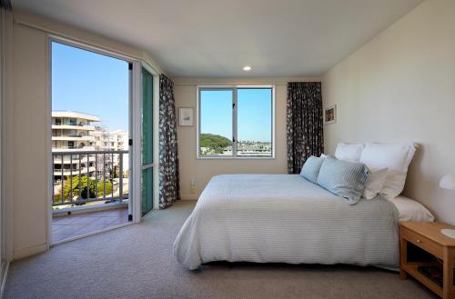 a bedroom with a bed and a large window at Beaumont Apartments in Mount Maunganui