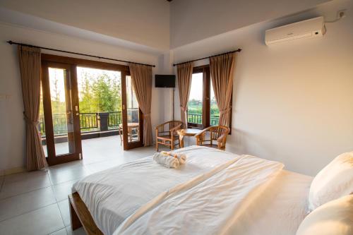 a bedroom with a bed and a balcony with windows at Pande Homestay in Canggu