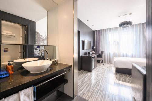 een badkamer met een wastafel en een slaapkamer met een bed bij Orange Hotel Hangzhou Wenyi West Road in Hangzhou