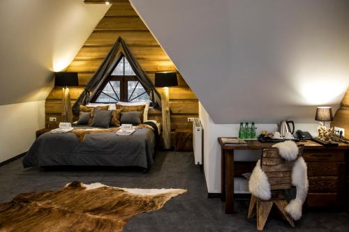 a bedroom with a bed and a desk in a attic at Pensjonat Orlik Mountain Resort&SPA in Bukowina Tatrzańska