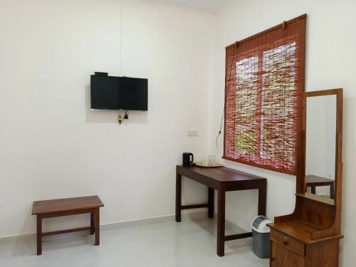 a room with a table and a mirror and a television at Didula Holiday Resort Anuradhapura in Anuradhapura