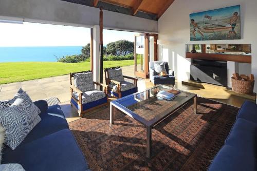 a living room with a blue couch and a glass table at The Pah - Stay Waiheke in Onetangi