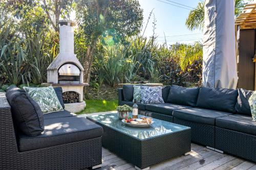 a patio with a couch and a table and a fireplace at Welcome Cottage - Stay Waiheke in Oneroa