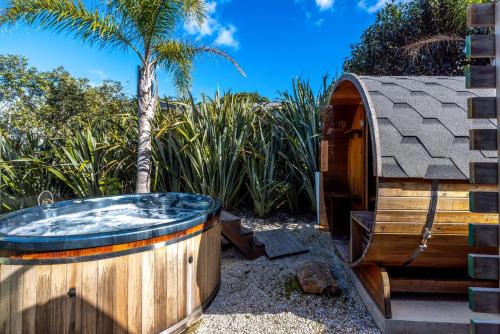 a wooden tub in a yard with a palm tree at Welcome Cottage - Stay Waiheke in Oneroa