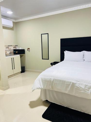 a bedroom with a large white bed and a mirror at PholaBnB in Pongola