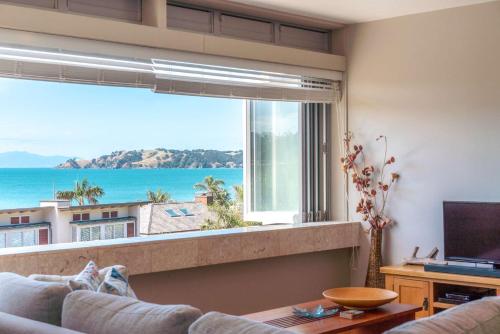 a living room with a large window with a view of the ocean at The Sands - Apartment 15 - Stay Waiheke in Onetangi