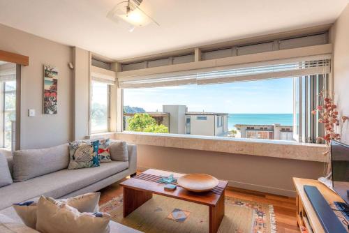 a living room with a couch and a large window at Horizon on The Beach at The Sands in Onetangi