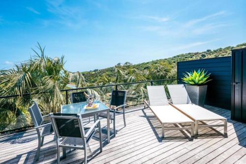 a patio with a table and chairs on a deck at Delamore Cove - Manuka - Stay Waiheke in Matiatia Bay