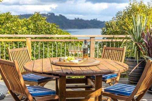 a wooden table and chairs on a deck at Seahorse Cottage - Stay Waiheke in Waiheke Island
