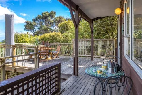 a porch with a table and chairs on it at Seahorse Cottage - Stay Waiheke in Waiheke Island