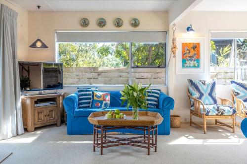 a living room with a blue couch and a tv at Seahorse Cottage - Stay Waiheke in Waiheke Island