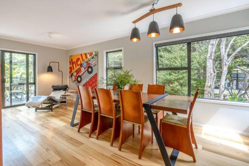 a dining room and living room with a table and chairs at Treetop Escape - Stay Waiheke in Waiheke Island