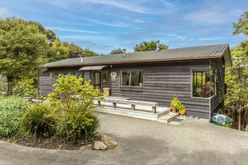 a tiny house with a porch in the woods at Treetop Escape - Stay Waiheke in Waiheke Island