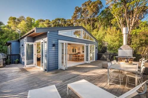 a blue tiny house with a deck with a table and chairs at Skyview Onetangi - Stay Waiheke in Waiheke Island
