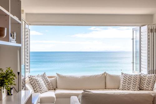 a living room with a white couch and a large window at The Sands Apartment 8 - Stay Waiheke in Waiheke Island