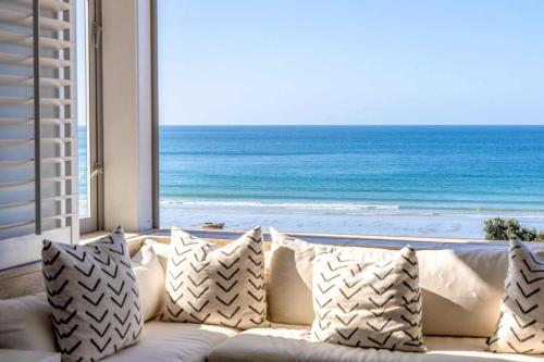 a couch sitting in front of a window with the ocean at The Sands Apartment 8 - Stay Waiheke in Waiheke Island