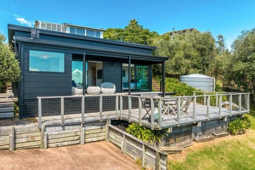 a house with a large deck in the yard at Black Cottage - Stay Waiheke in Waiheke Island