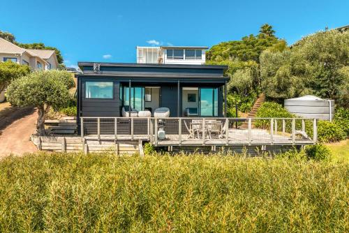 una casa sentada en la cima de un campo de hierba en Black Cottage - Stay Waiheke, en Waiheke Island