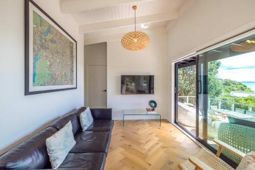 Una sala de estar con un sofá y una ventana grande. en Black Cottage - Stay Waiheke, en Waiheke Island