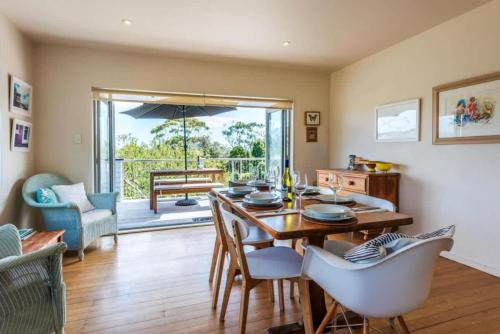 comedor con mesa con sillas y sombrilla en Beachlovers Onetangi - Stay Waiheke, en Waiheke Island