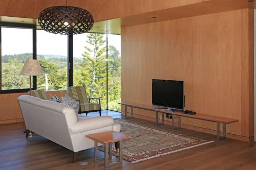 a living room with a couch and a tv at Number Five - Stay Waiheke in Onetangi