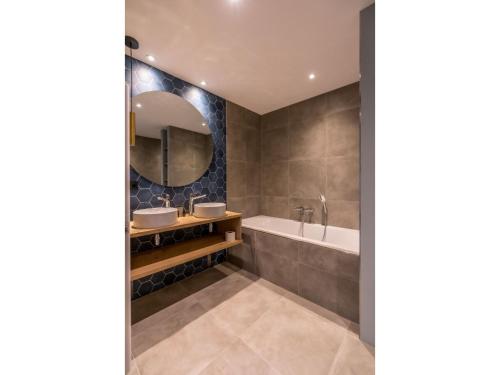 Modern villa in De Cocksdorp near the beach في دي كوكْسدوربْ: حمام به مغسلتين وحوض استحمام ومرآة